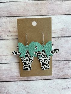 two giraffes with green leaves on them are hanging from a brown card