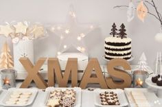 a table topped with cakes and desserts next to a wooden xmas sign