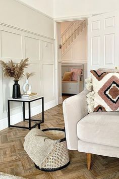 a living room with white walls and wood flooring on the wooden floor is decorated in neutral tones