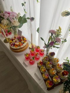 there are many desserts on the table with flowers in vases and candles behind them