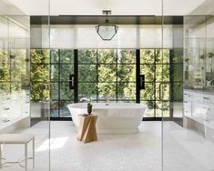 a large bathroom with glass walls and a white bathtub next to a walk in shower