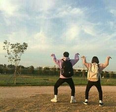 two people standing on top of a dirt field