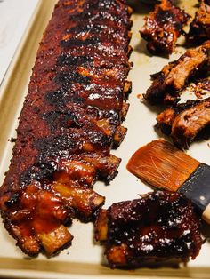 bbq ribs and barbecue sauce on a tray with a spatula next to them