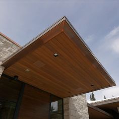 the roof of a modern house with stone and wood siding on it's sides