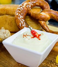 an assortment of pretzels and dips on a cutting board with bread in the background