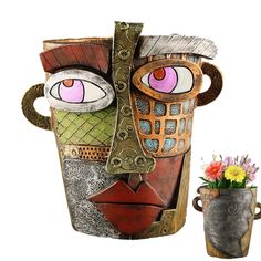 a vase with flowers in it next to a mask