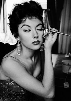 a black and white photo of a woman getting her make - up done