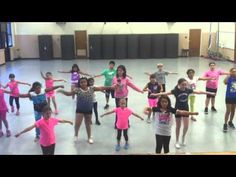 a group of children in pink shirts are dancing