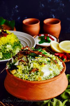 a bowl filled with food sitting on top of a table next to two plates and cups