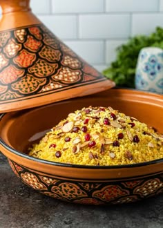 a bowl filled with rice and nuts on top of a table next to a vase