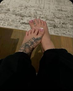 a woman's foot with tattoos on it sitting in front of a rug