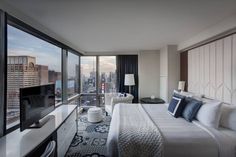 a hotel room with a large bed and a view of the city outside it's windows