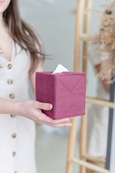 a woman holding a pink box with tissue in it