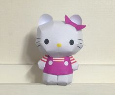 a hello kitty stuffed animal sitting on top of a white shelf next to a wall