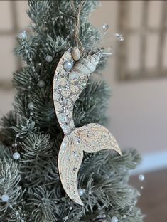 an ornament hanging from a christmas tree in the shape of a mermaid's tail