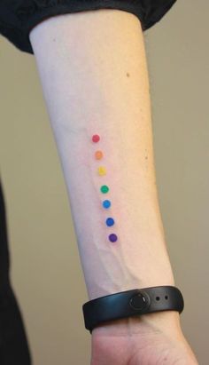 a woman's wrist with a colorful dot tattoo on the left side of her arm