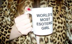 a woman is holding a coffee mug in her right hand while wearing leopard print coat