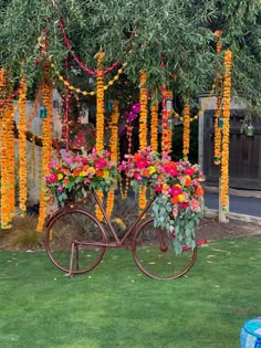 a bicycle with flowers on the back is parked in front of a tree filled with orange and pink flowers