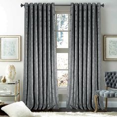 a living room filled with furniture and a window covered in grey drapes, next to a white rug