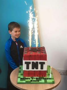 a young boy standing in front of a cake made to look like a lego block