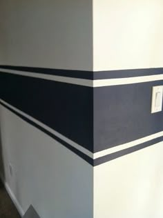 the corner of a room painted in black and white with a light switch on it