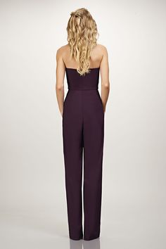 the back view of a woman in a purple strapless jumpsuit, looking down at her