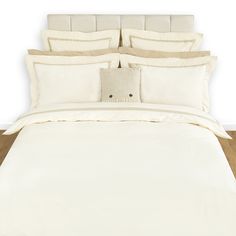 a bed with white sheets and pillows on top of it