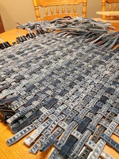 a wooden table topped with lots of cut up pieces of blue jean fabric on top of it