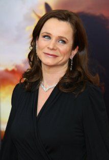 a woman in a black dress posing for the camera with her eyes wide open and smiling