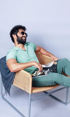 a man sitting in a chair with sunglasses on his face and holding a book while looking at the camera