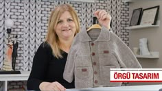 a woman holding up a coat in front of a desk