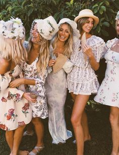 four women in dresses and hats posing for a photo