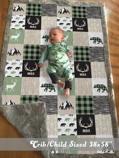 a baby laying on top of a blanket with deer and moose designs in the background