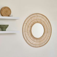 a round mirror sitting on top of a white shelf next to a wall mounted shelf