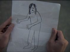 someone holding up a paper with a drawing of a man on it