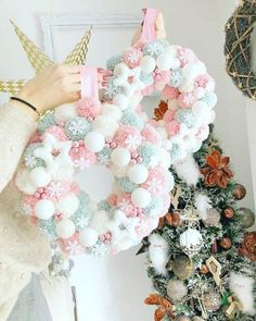 a woman is holding a wreath with pom poms on it