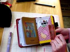 a person holding an open book on top of a table