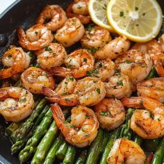 shrimp and asparagus on a skillet with lemon wedged in the middle