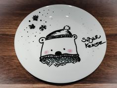 a white plate with a cartoon bear wearing a santa hat on it's face