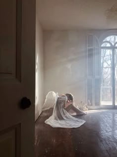 a woman is sitting on the floor in front of an open door with angel wings