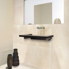 a bathroom with a sink, mirror and vase on the counter