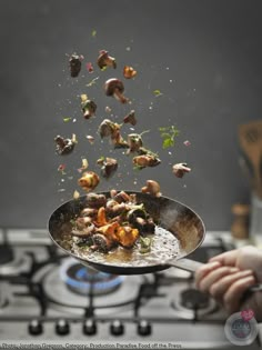 a person holding a frying pan full of food over a stove top burner