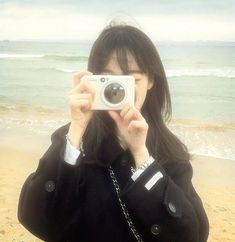 a woman taking a photo with her camera on the beach