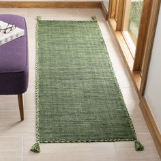 a green rug on the floor next to a purple chair