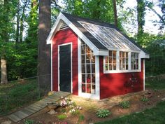 a small red and white shed in the woods