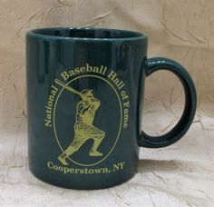 a green coffee mug with a baseball hall of fame logo on it