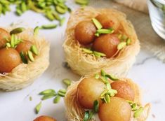 three small baskets filled with food sitting on top of a white tablecloth next to green leaves