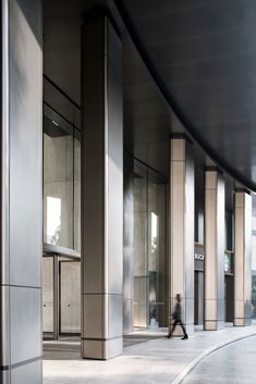 a man is walking down the sidewalk in front of an office building with glass doors