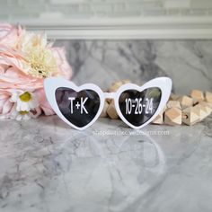 two heart shaped sunglasses with the words tk and k on them next to flowers