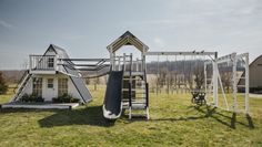 an outdoor play set in the middle of a field with a slide and climbing frame